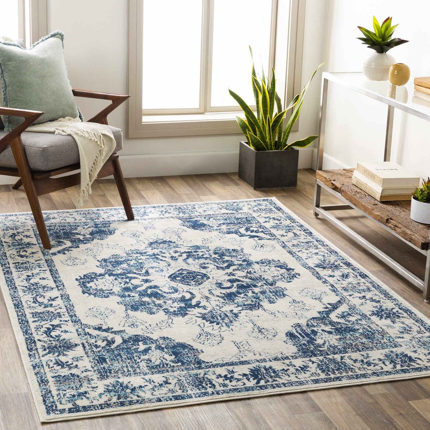 Living room scene with a blue and beige Helidon Area Rug, gray chair, and wood floors. Roomscene-Rectangle