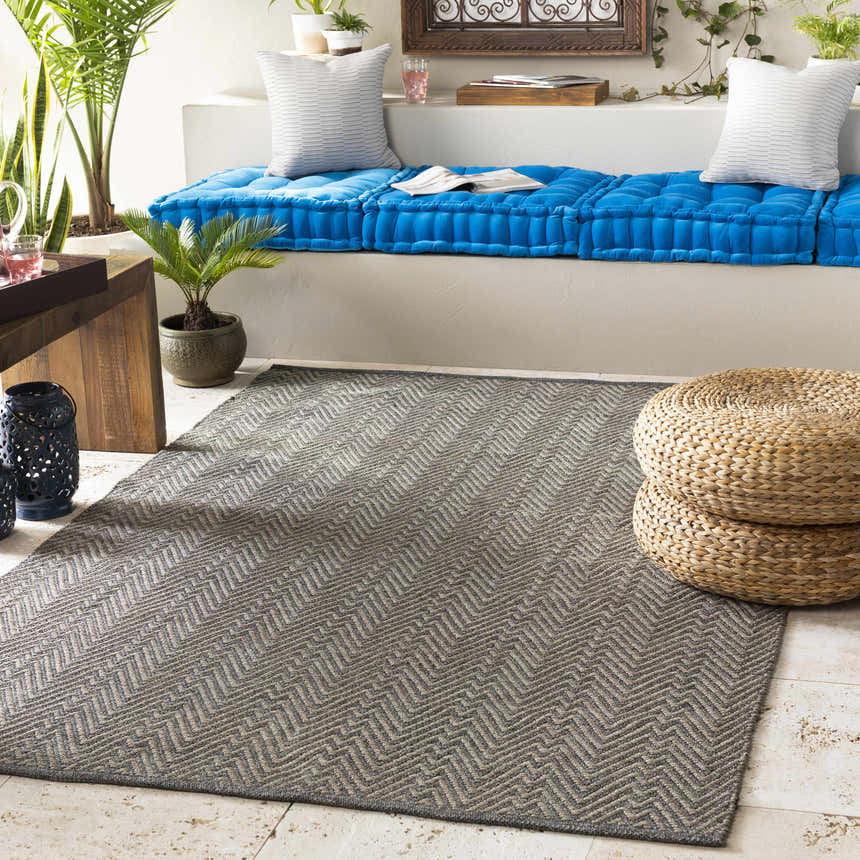 Relaxed sunroom with blue cushions and a Herlong Charcoal Herringbone Rug. Roomscene-Rectangle