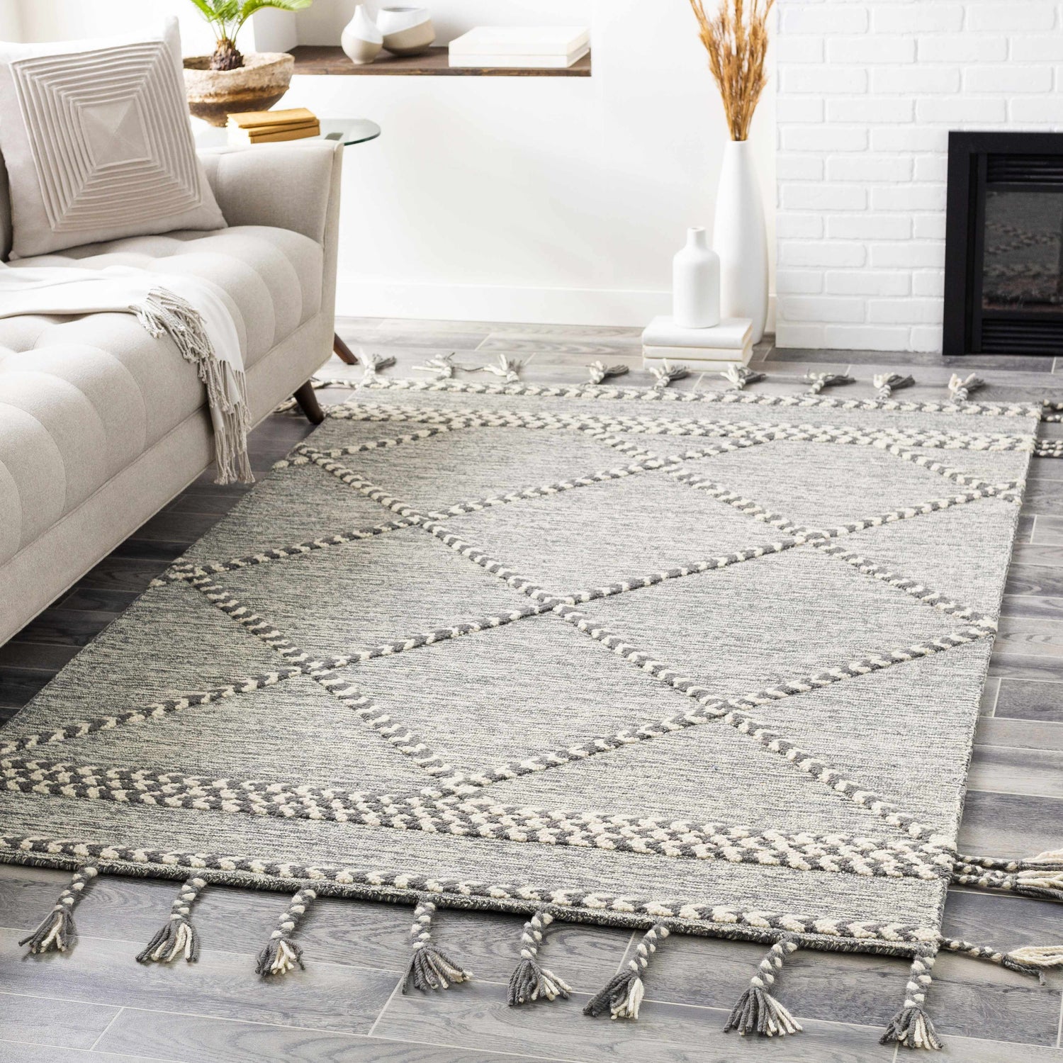 Living room scene with Hertfordshire Gray Trellis Tassel Wool Rug, sofa, fireplace, and gray wood floors. Roomscene-Rectangle