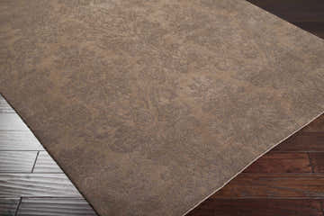 Close-up of the Heywood Area Carpet in mocha with a traditional floral design on dark wood floors. Corner