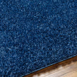 Close-up of the plush texture and dark blue color of the Faina Solid Shag Washable Area Rug. Texture