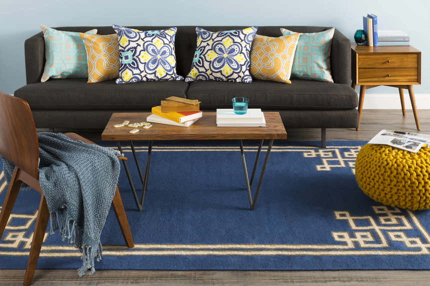 Living room scene with blue Hinckley Area Rug, gray sofa, wood coffee table, and yellow pouf. Roomscene-Rectangle