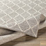 Close-up of the hand woven Hindley Area Rug. Cream and gray wool rug with a contemporary diamond pattern. Fold
