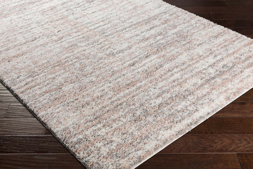 Close-up of the plush Hammond Dusty Pink Rug showing cream, pink, and gray tones and soft texture on dark wood floors. Corner