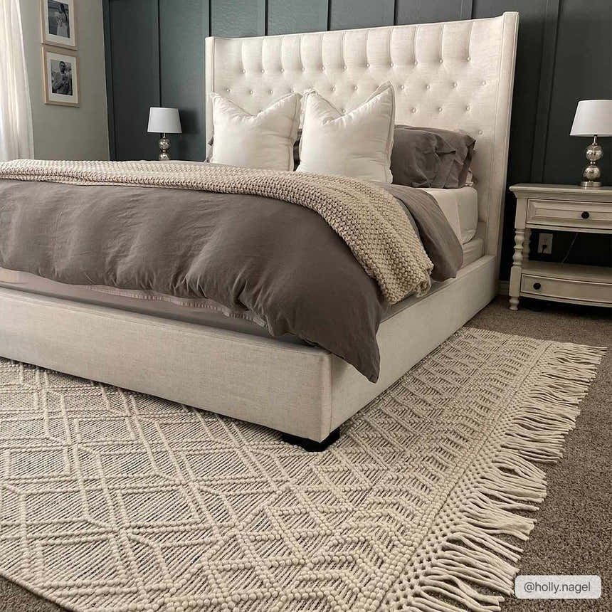 Bedroom scene with a cream upholstered bed and the cream geometric Ossun Wool Rug with Tassels. Roomscene-Rectangle