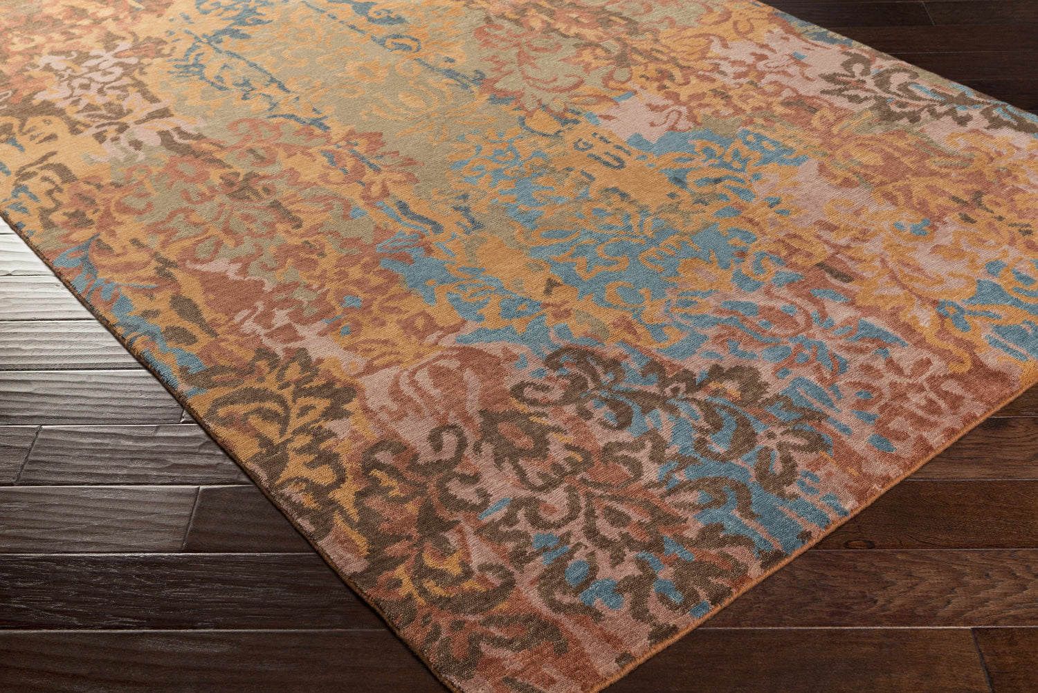 Close-up of the hand-knotted Homerville Area Rug. The rug features a contemporary floral pattern in tan, rust, blue, and sage. Corner