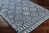 Close up of the Horton Modern Wool Rug, featuring a navy and white geometric pattern on dark wood floors. Corner