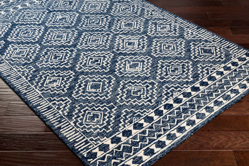 Close up of the Horton Modern Wool Rug, featuring a navy and white geometric pattern on dark wood floors. Corner