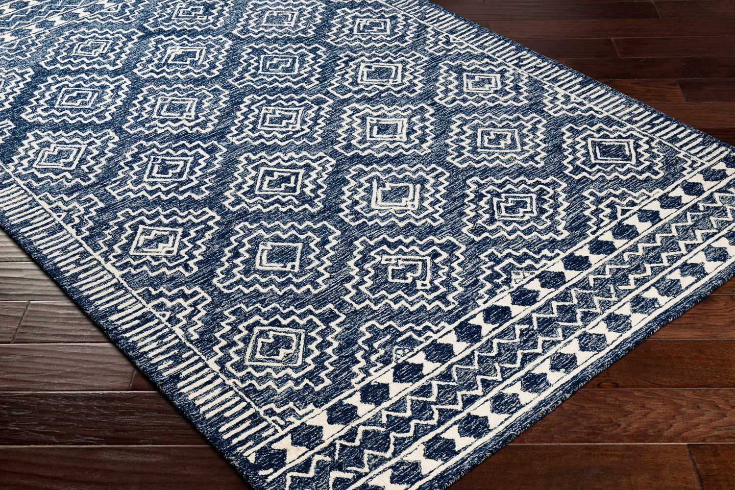 Close up of the Horton Modern Wool Rug, featuring a navy and white geometric pattern on dark wood floors. Corner