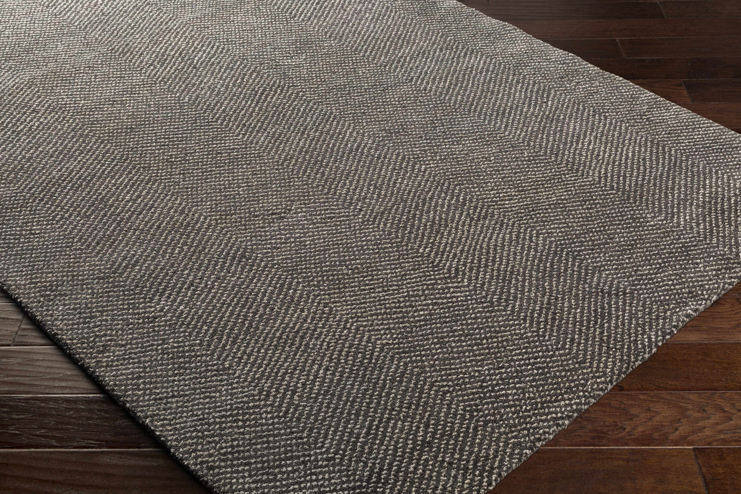 Close-up of the Hoyt Carpet in charcoal and off-white, showing its hand-knotted construction and contemporary chevron pattern. Corner