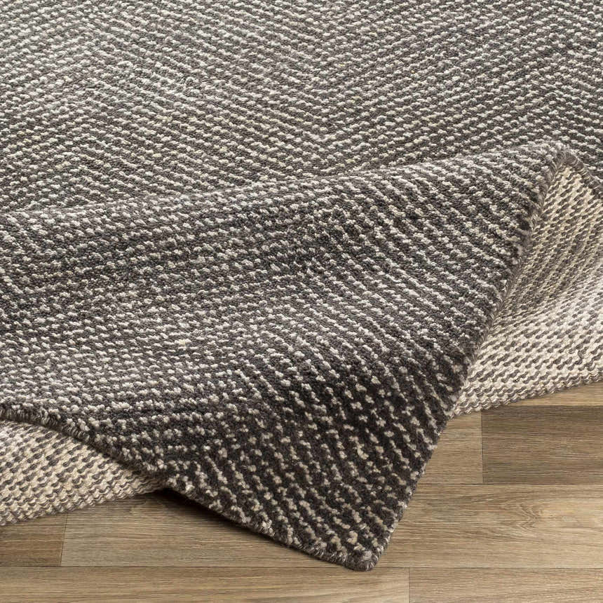 Close-up of the hand-knotted Hoyt Carpet, a contemporary rug in charcoal and off-white wool and viscose blend. Fold
