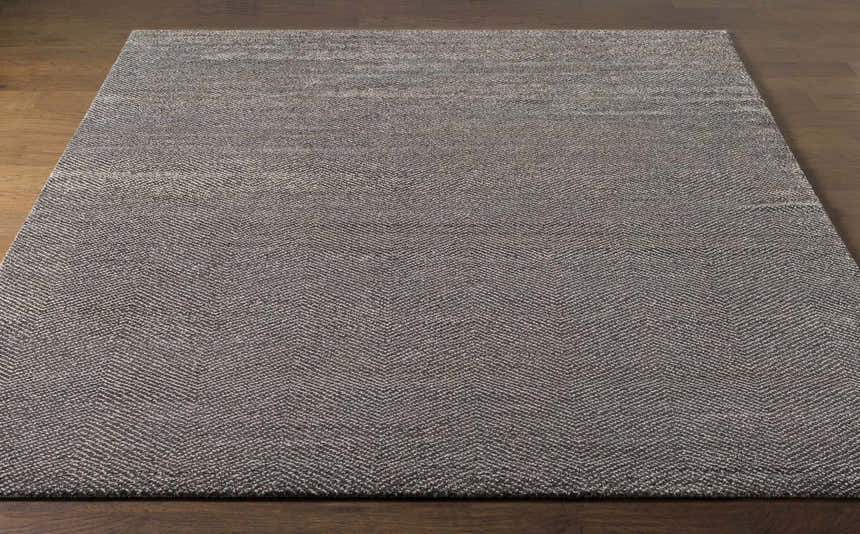 Close-up of the Hoyt Carpet, a charcoal and off-white hand-knotted rug with a contemporary herringbone pattern. Front
