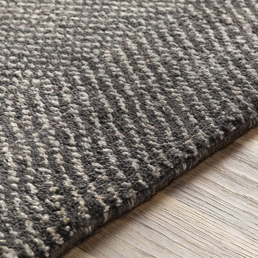 Close-up of the Hoyt Carpet, a hand-knotted rug with a charcoal and off-white contemporary design. Viscose and wool texture. Texture