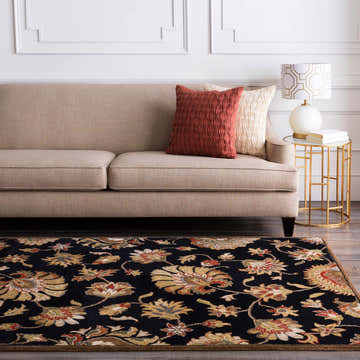 Living room scene with a black Huxley Area Rug featuring a floral pattern, beige sofa, and gold side table. Roomscene-Rectangle