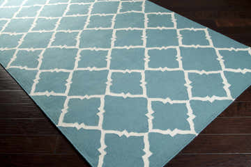Close-up of the Haverhill Area Rug showing its seafoam color and white geometric trellis pattern. 100% wool, hand woven. Corner