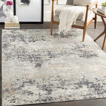 Living room scene with a gray chair and the charcoal, gray, and mustard Hyner Area Rug. Roomscene-Rectangle