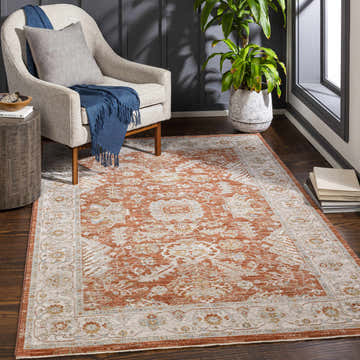 Living room scene with brick red Ibstock Thick Luxe Area Rug, beige chair, and dark wood floors. Roomscene-Rectangle