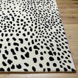Close-up of the Athena White Giraffe Print Wool Rug. Black spots on off-white, hand-tufted texture. Contemporary style. Front