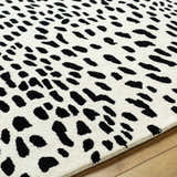 Close-up of the Athena White Giraffe Print Wool Rug. Features a black giraffe print on an off-white, hand-tufted wool rug. Texture