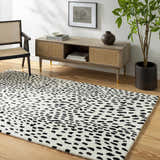 Living room scene with a modern Athena White Giraffe Print Wool Rug, wood floors, console table, and black accent chair. Roomscene-Rectangle