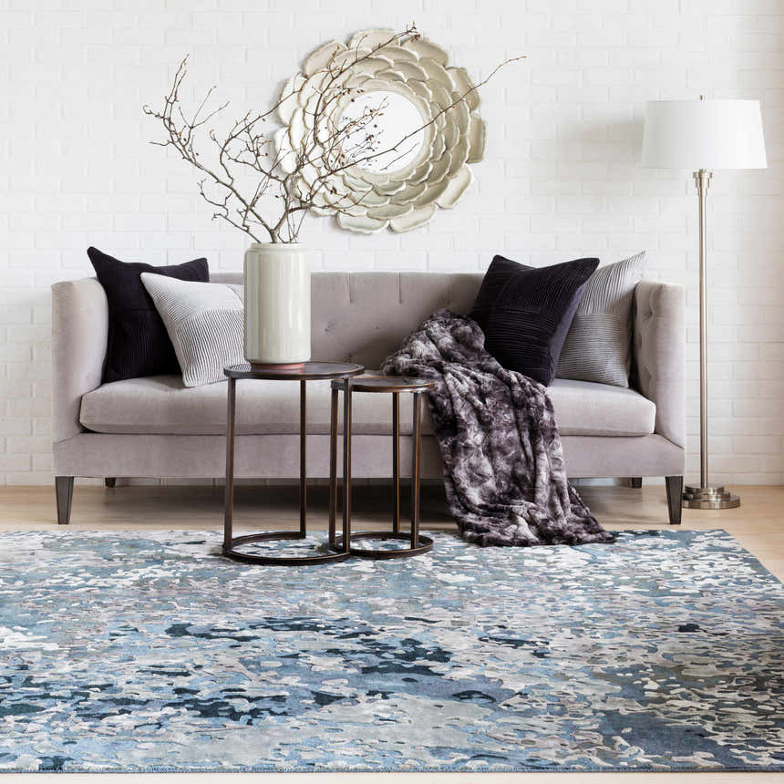 Living room scene with a blue and gray Ingomar Area Rug, gray sofa, and white brick wall. Roomscene-Rectangle