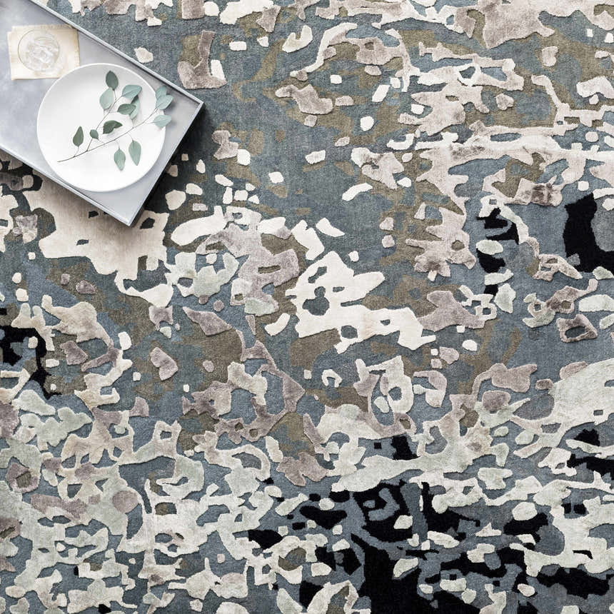 Close-up of the hand-knotted Ingomar Area Rug. Viscose rug in black, denim, dusty sage, gray, navy, and off-white. Styleshot