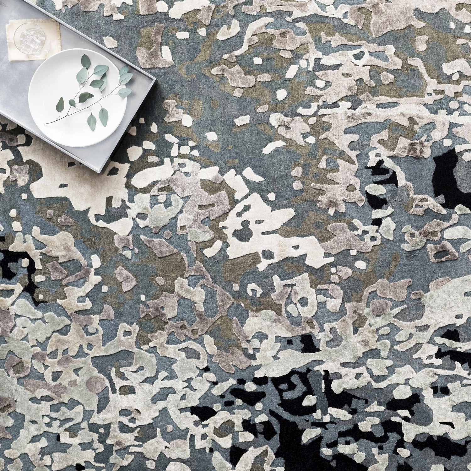 Close-up of the hand-knotted Ingomar Area Rug. Viscose rug in black, denim, dusty sage, gray, navy, and off-white. Styleshot