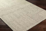 Close-up of the hand-tufted Isamu Area Rug. Dusty sage and medium gray wool rug with a geometric pattern. Corner