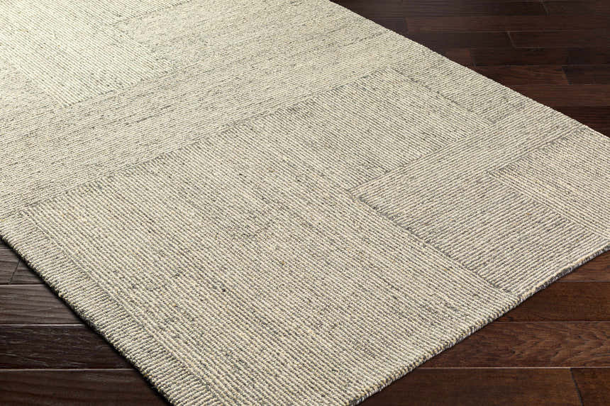 Close-up of the hand-tufted Isamu Area Rug. Dusty sage and medium gray wool rug with a geometric pattern. Corner