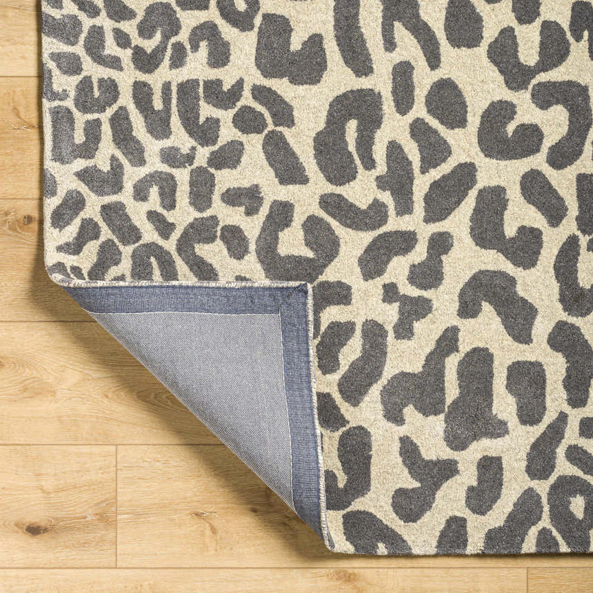 Close-up of the Iseul Leopard Print Area Rug. Hand-tufted wool rug with a dark gray and taupe animal print pattern. Fold