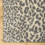 Close-up of the Iseul Leopard Print Area Rug, a hand-tufted wool rug with a dark gray leopard pattern on a taupe background. Corner