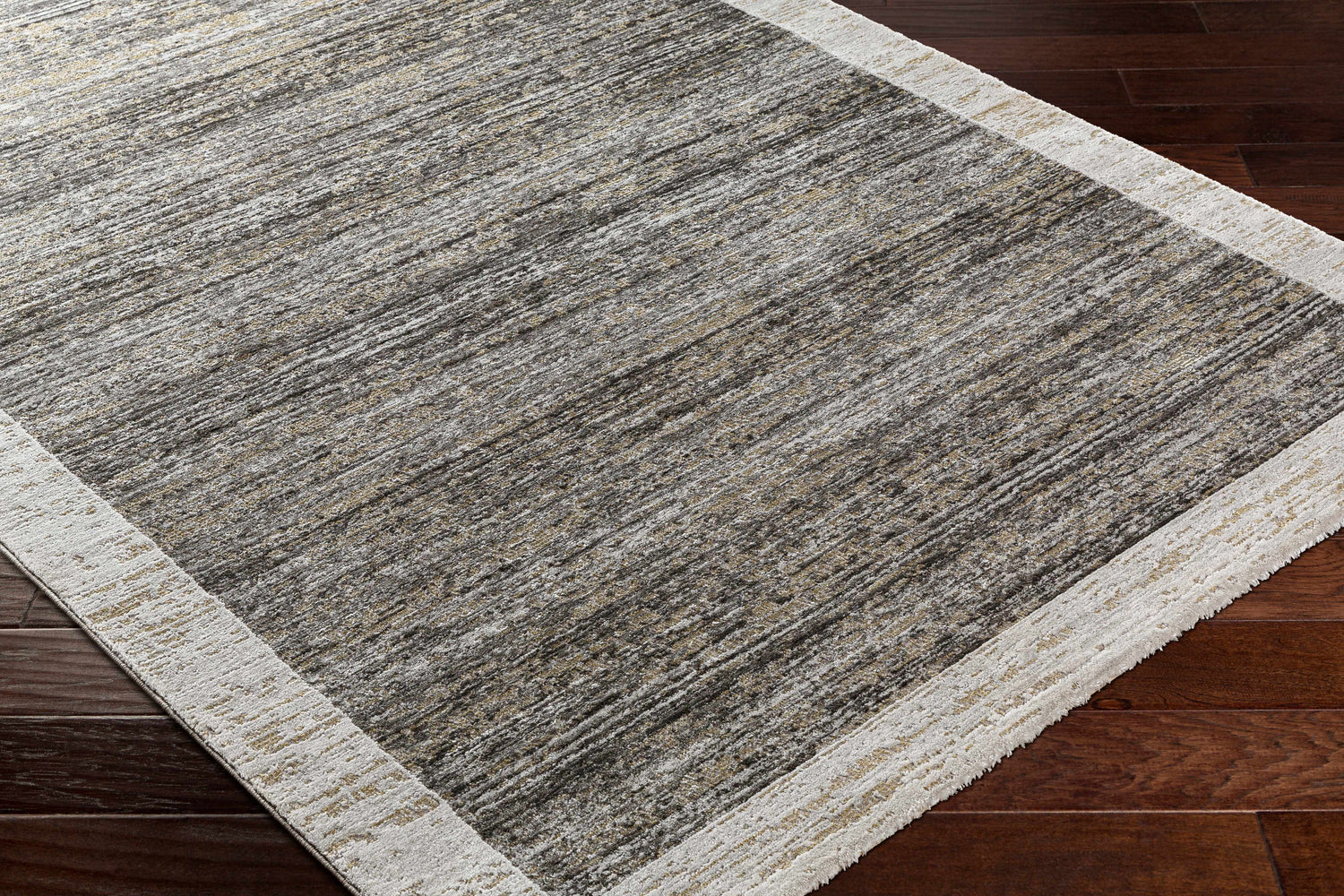 Close-up of the Ishik Area Rug. Contemporary style with charcoal, brown, and gray striations. Neutral border. Corner
