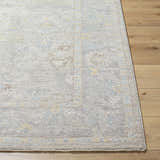 Close-up of the Istas Thick Luxe Area Rug in cloud gray, showing the traditional pattern and soft texture on wood floors. Front
