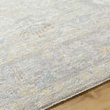 Close-up of the Istas Thick Luxe Area Rug in cloud gray, lambswool, and light brown with a traditional pattern. Texture