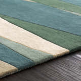 Close up of the Jarratt Modern Wool Rug showing cream, green and teal stripes on a dark wood floor. Texture