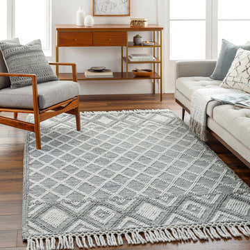 Living room scene with gray sofa and chair, featuring a gray and white geometric Jaya Area Rug. Roomscene-Rectangle