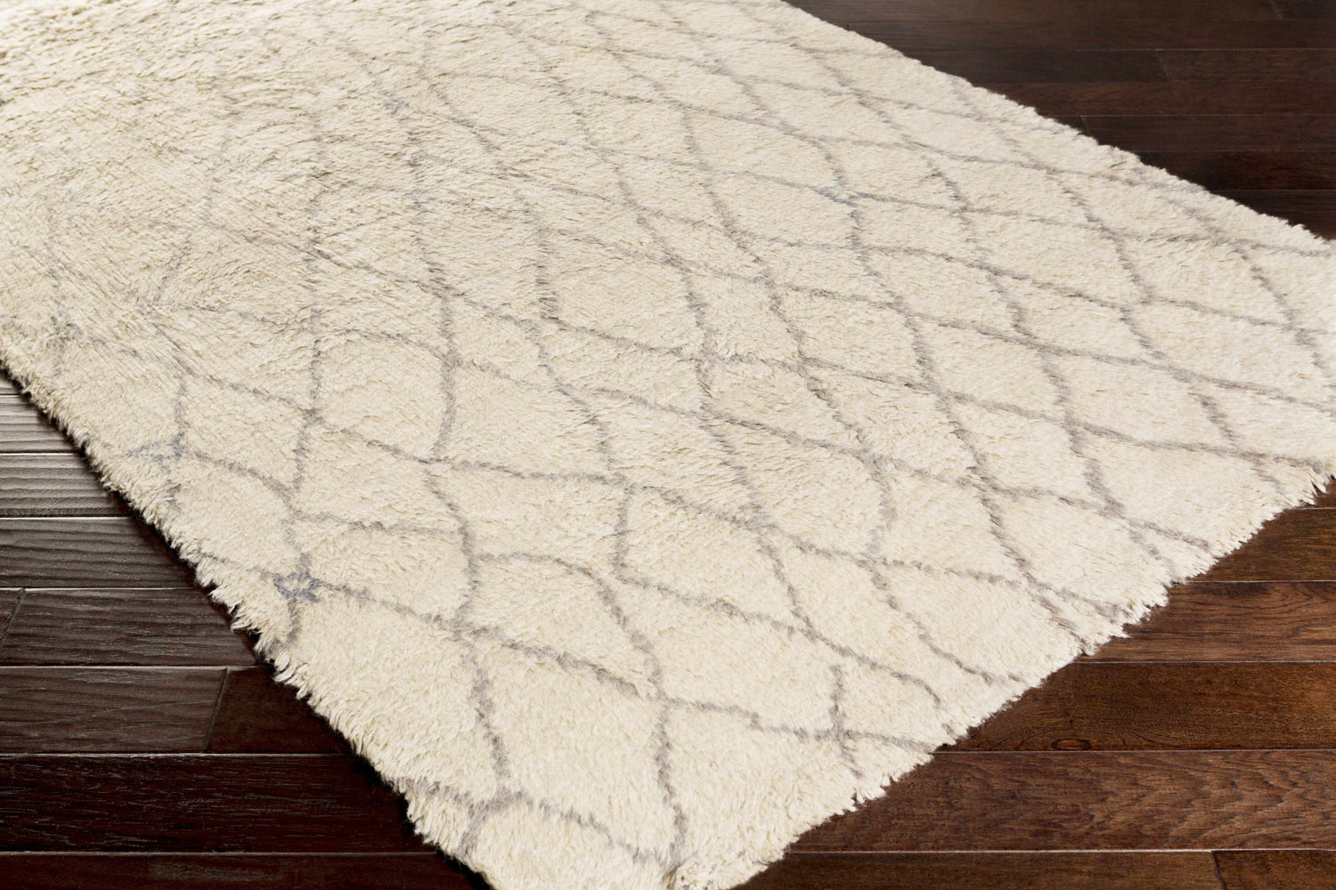 Close-up of the hand-knotted Jeddo Area Rug. Ivory wool rug with a charcoal geometric diamond pattern. Farmhouse style. Corner