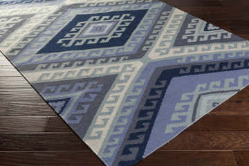 Close-up of the Johnsburg Area Rug. Hand-woven wool rug with a geometric diamond pattern in denim, light gray, navy, and pale blue. Corner