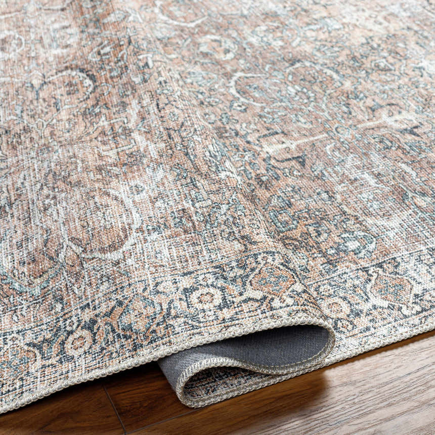 Close-up of the Jill Washable Area Rug, showcasing its brown, blue, and saffron vintage Persian-style design and woven texture. Fold