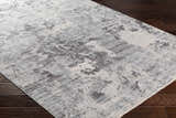 Close-up of the Johnetta Carved Statement Rug in ivory, gray, and charcoal on a dark wood floor. Abstract, contemporary style. Corner