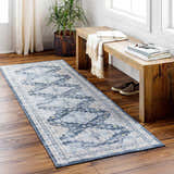 Entryway with wood floors and Jara Washable Area Rug in dark gray and denim, styled with a wood bench and plant. Roomscene-Runner