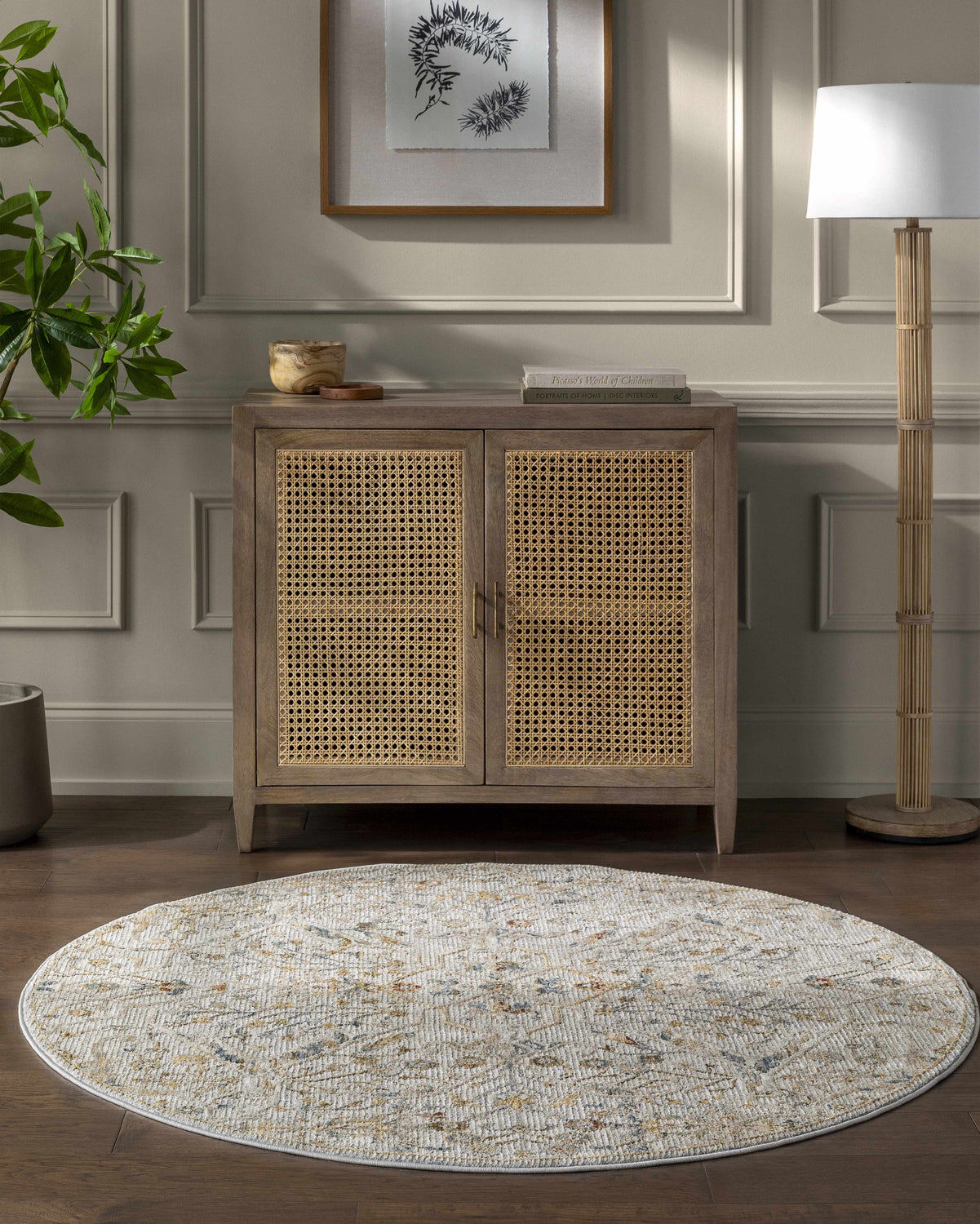 Entryway with a round Kabungahan Oushak Style Floral Rug, wood cabinet, lamp, and plant on a dark wood floor. Roomscene-Round