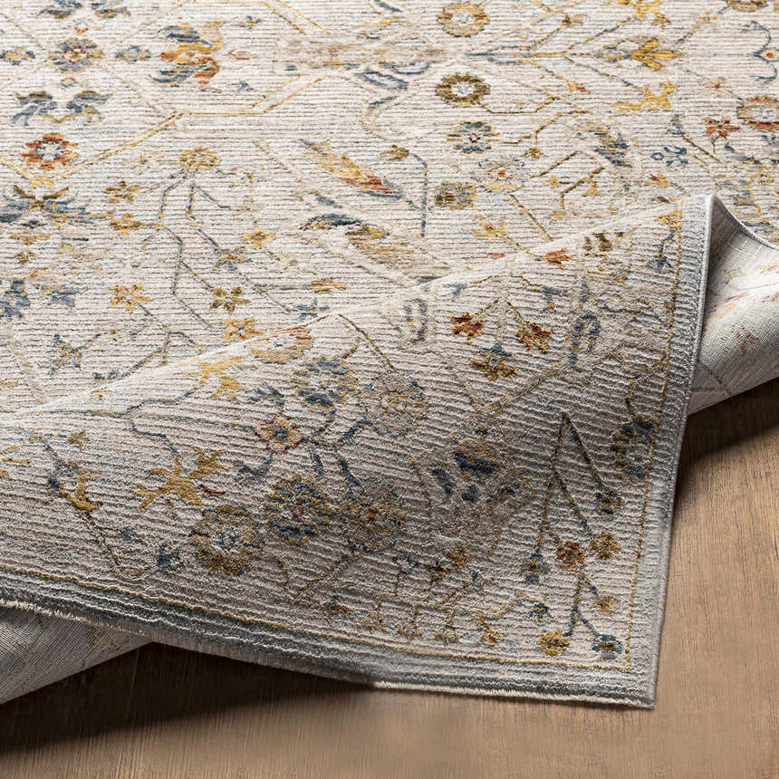 Close-up of the Kabungahan Oushak Style Floral Rug. Features a traditional floral pattern in brick red, cream, denim, and mustard. Fold