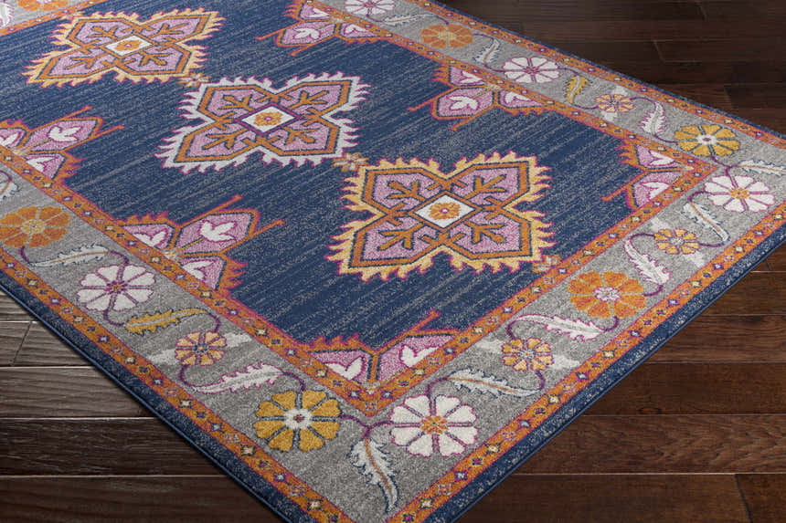 Close-up of Kaitlyn Navy Area Rug. Features a traditional floral and geometric design in navy, orange, and gray. Corner