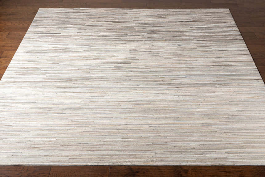 Close-up of Karabar Premium Area Rug. Beige, brown, and off-white hair on hide strips create a textured, Scandinavian design. Front