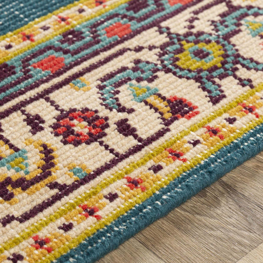 Close-up of the hand-knotted Kaser Carpet. Features a traditional design with dark plum, teal, and mustard colors on a beige background. Texture