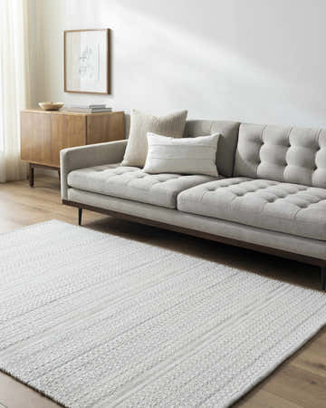 Living room scene with a light gray Kendi Wool Rug, sofa, and wood cabinet. Roomscene-Rectangle