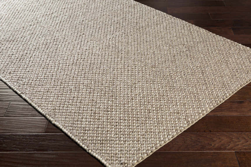 Close-up of the hand woven Keldron Clearance Rug. Charcoal and cream fibers with a textured, contemporary design. Corner