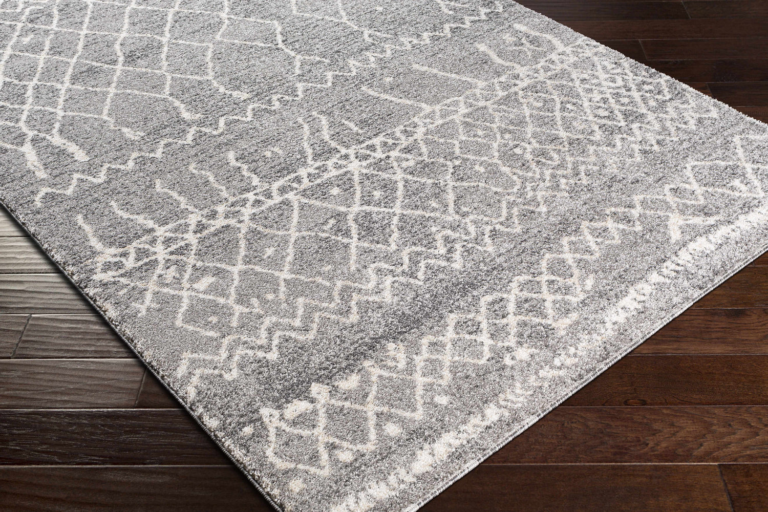Close up of the Kessingland Area Rug, a gray rug with a white geometric pattern. Corner