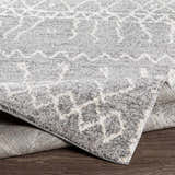 Close-up of the Kessingland Area Rug showing its gray and white geometric pattern and soft, textured pile. Fold